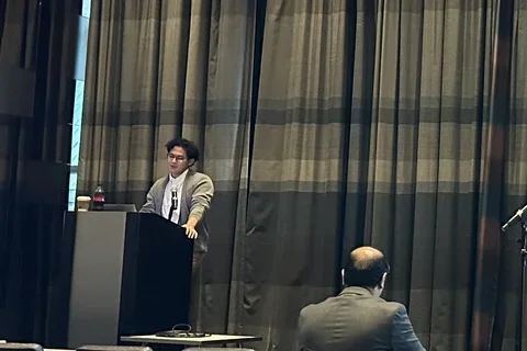 Irsyad Adam standing at a podium presenting his ATHENA work.